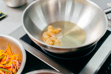 Close up photo of chef preparing fresh shrimps in pan with oil