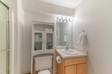 White bathroom interior with over-the-toilet storage cabinet