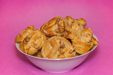 Homemade buns with sugar in a white ceramic plate on a pink background