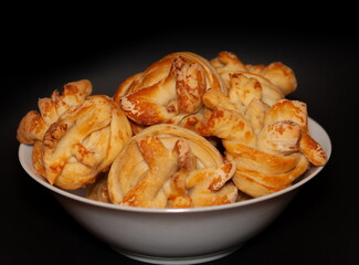 Homemade buns with sugar in a white ceramic plate on a black background