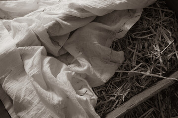 rustic manger from nativity with white linen and straw close up from above