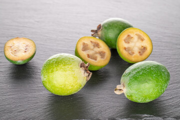 Several fragrant sweet feijoa fruits on a slate stone, close-up.