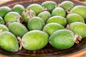 Several fragrant sweet feijoa fruits in earthenware, close-up.