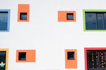 Kindergarten creative building with colorful windows. Colored windows on a white wall. Orange, red, green, blue, yellow