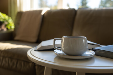 cup of coffee on round white table in living room by leather sofa with open bible book