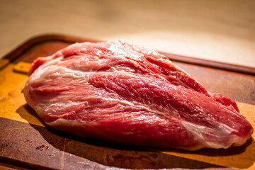 The butchered thigh of a turkey lies on a wooden board