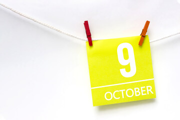 October 9th. Day 9 of month, Calendar date. Paper cards with calendar day hanging rope with clothespins on white background. Autumn month, day of the year concept.