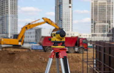 Photo of a level at the construction site of multi-storey buildings with a yellow excavator and an red truck on the street in the city