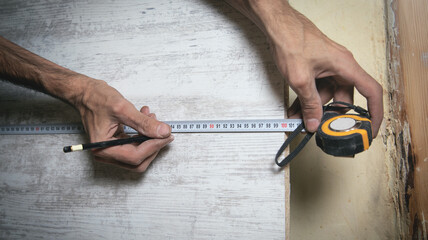 Carpenter marking laminate with tape measure and pencil.