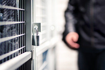 Burglar or thief and storage with lock in basement of condo apartment building. Suspicious man,...