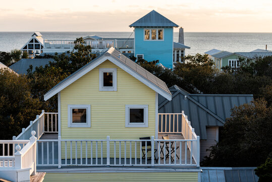 High angle aerial view on colorful sunset with ocean landscape of Gulf of Mexico in Seaside, Florida from wooden rooftop buildings yellow houses cityscape
