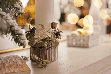 christmas decorations on mantelpiece at home in white gold colors with lights