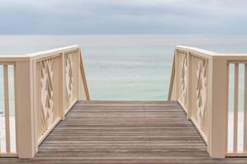 High angle view of wooden pavilion boardwalk railing stairs steps leading to beach at Gulf of Mexico at Seaside, Florida on cloudy day