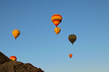 Obraz premium Goreme, Turkey-October 9,2021:Air balloons festival in Cappadocia. Few hot air balloons against colorful vibrant sky. Picturesque nature landscape in the background