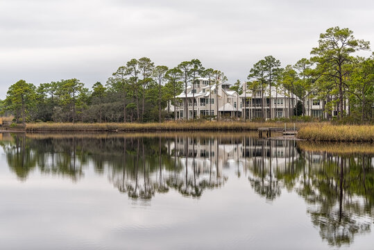 Western lake in Seaside, Florida Gulf of Mexico on cloudy day with lake house reflection and pine trees in winter