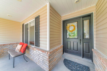 Black front door with ornate glass panels and yellow wreath