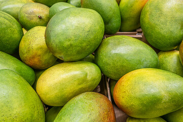 ruit background of ripe fragrant green mangoes on the market counter