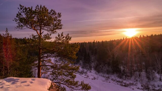 Colorful winter sunset above the forest and frozen river timelapse 4K