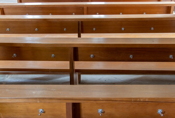 A empty pews in the church with hooks on his back side.