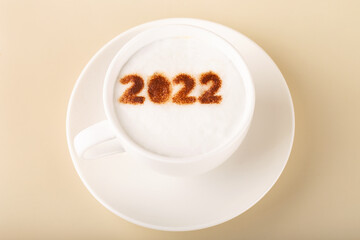 cappuccino in white cup with the inscription 2022, new year, beige background