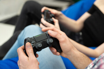 Close-up of the hands of a man and a woman enjoying playing video games  with a console gamepad in their hands.