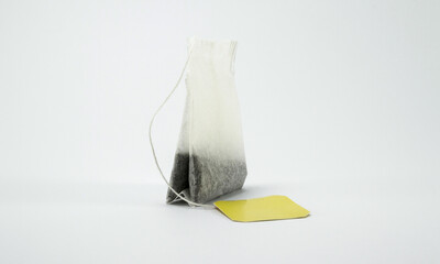 Tea bag with yellow tag on white background.	 - Powered by Adobe