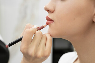 Lip makeup. Close-up of a cosmetologist painting her lips with a pencil before permanent makeup