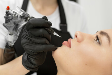 Cosmetologist applies permanent makeup to the lips in the salon.