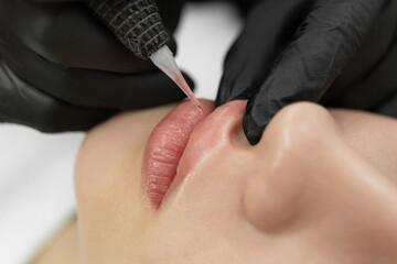 Close-up of the permanent makeup procedure. Lip makeup in the cosmetologist's salon. - obrazy, fototapety, plakaty
