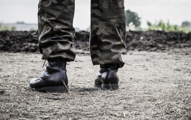 Close-up of soldier's legs on a battlefield, wearing military boots and woodland camo pants...