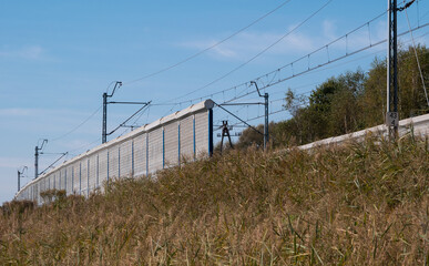 Obraz premium Railroad noise barrier. Acoustic wall reducing train sound. Soundproof protection fence along the railway.