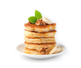 A stack of pancakes with nuts, banana, mint and honey in a white plate isolated on white.