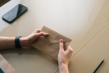 Close-up top view of unrecognizable young woman holding in hands envelope with received letter...