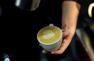Hand of professional barista making cappuccino coffee pouring milk. Barista making latte in cup with milk.