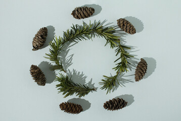 Pine cones and fir tree sprigs arranged in a circle on a white background. Flat lay. Copy space. Modern minimalist Christmas pattern. Organic Christmas concept. Winter holiday composition.