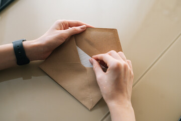 Close-up high-angle view of unrecognizable young woman holding in hands envelope with received...