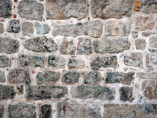 Fragment of ancient house's wall made of different sizes gray stones. Horizontal shot. 