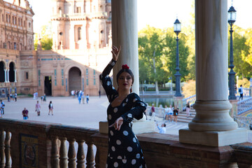 Spanish, beautiful, brunette flamenco dancer with a typical flamenco dress in black with white polka dots. She is dancing in the park in Seville. Flamenco concept cultural heritage of humanity.