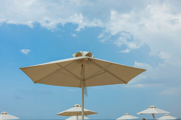 Beautiful view of white sand beach with sun umbrella and sunbed. Greece.