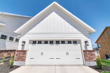 Exterior of a garage with white wood and red bricks siding