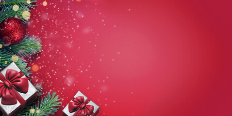 Red background with fir branches, ball and gift box. Christmas decoration.