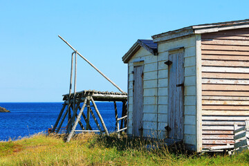 Fototapeta na wymiar A fishing stage and fishing sheds on a grassy hill, next to the Atlantic Ocean.