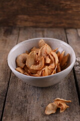 Dried apples in a bowl against a dark old wooden background