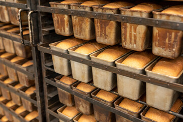 Metal racks with freshly baked loaves of fresh wheat bread. Fresh bread on a mobile rack with...