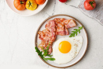 English breakfast. Egg and fried bacon. A cup with tomatoes. Serving breakfast on a marble table. Fried egg.