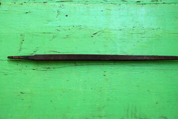 Old metal file. A medium-sized square file without a handle lies on a green wooden surface. Vintage tool for working on metal and wood.
