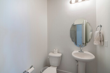 White powder room interior with shaped mirror and pedestal sink
