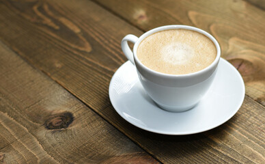 Close up white cup with cappuccino, wooden table, coffee ,copy space
