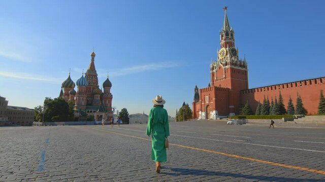 An attractive girl in a green dress walking to St. Basil's Cathedral