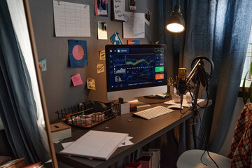 Image of computer monitor with financial graphs on the screen and microphone for online work at home